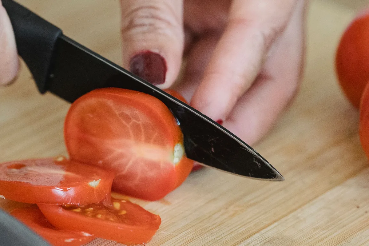 A sharp knife slicing a tomato