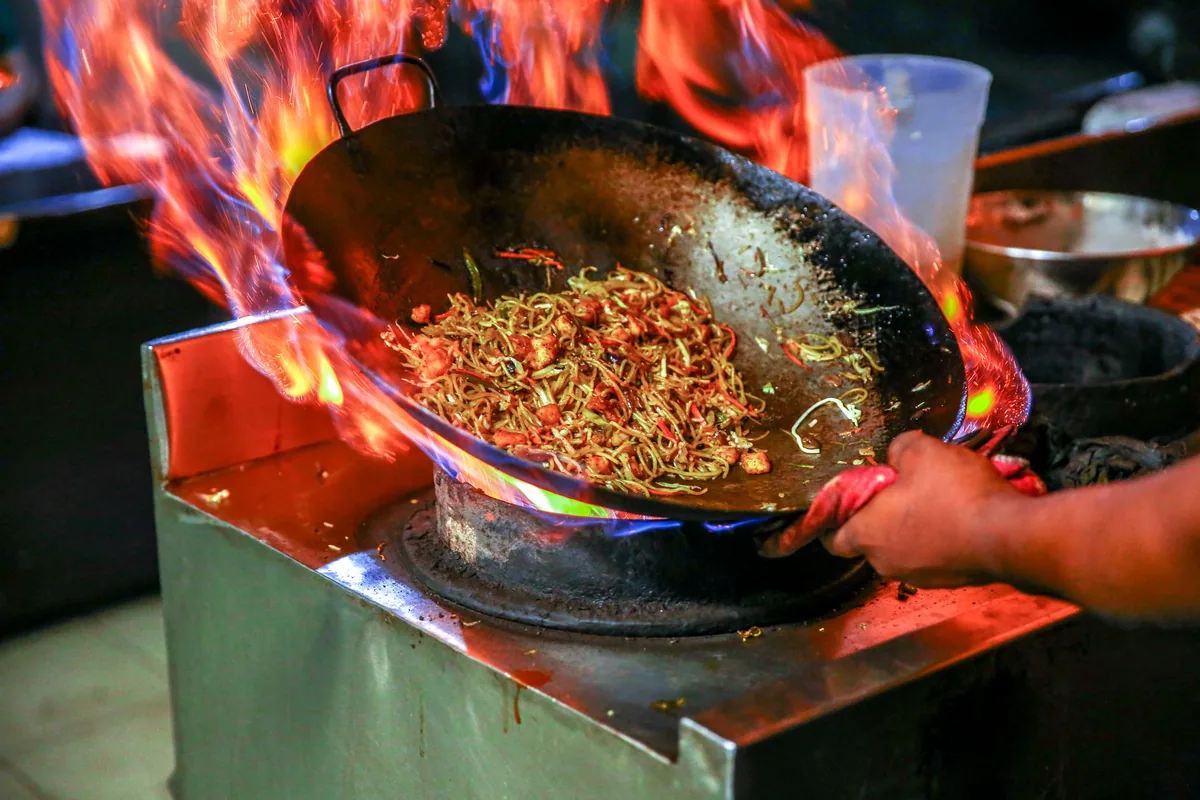 A wok tossing noodles