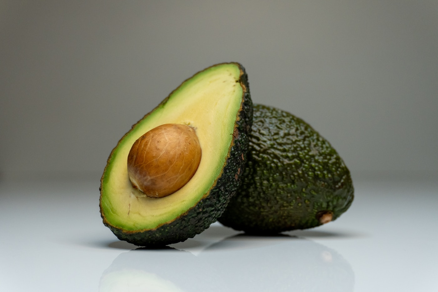 Fresh avocado cut in half on a white surface