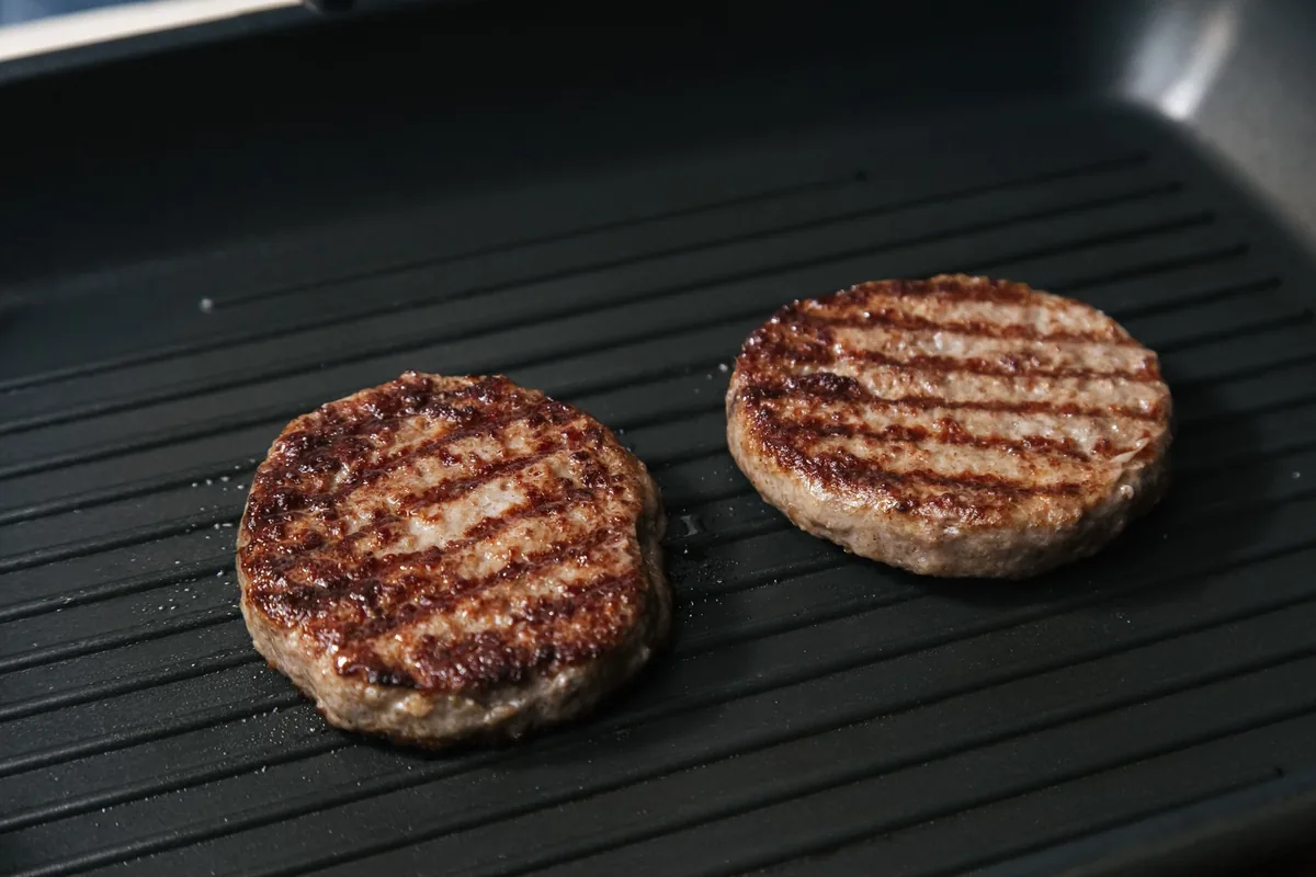 Beef patties cooking on a flat skillet
