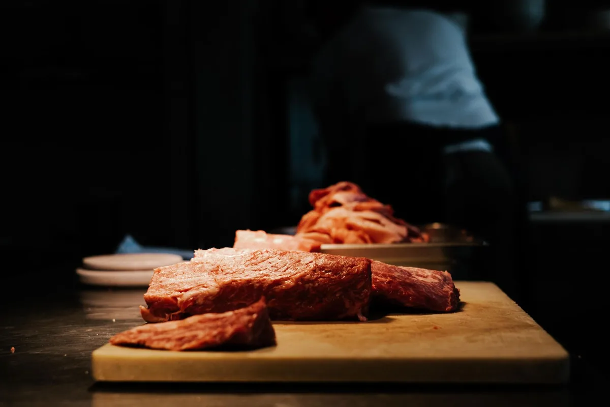 Slices of raw meat on a wooden cutting board