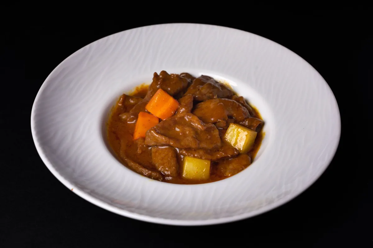 Beef stew with carrots and potatoes in a white bowl