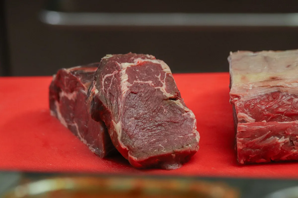 Raw beef pieces on a red cutting board