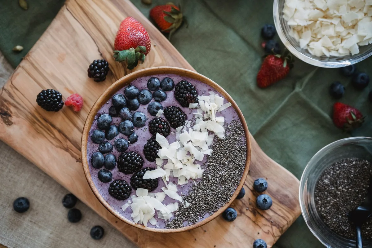 A berry smoothie bowl topped with fruit and seeds