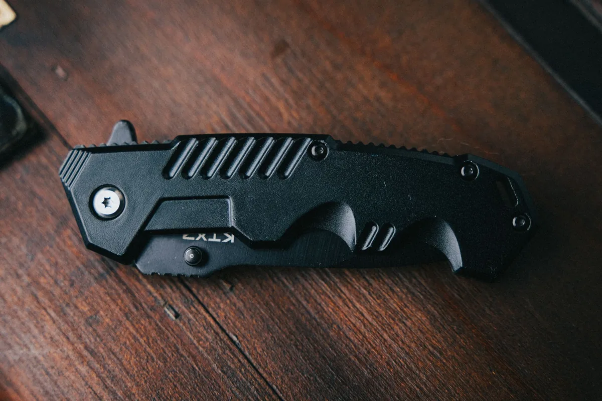 A black folding pocket knife on dark wood