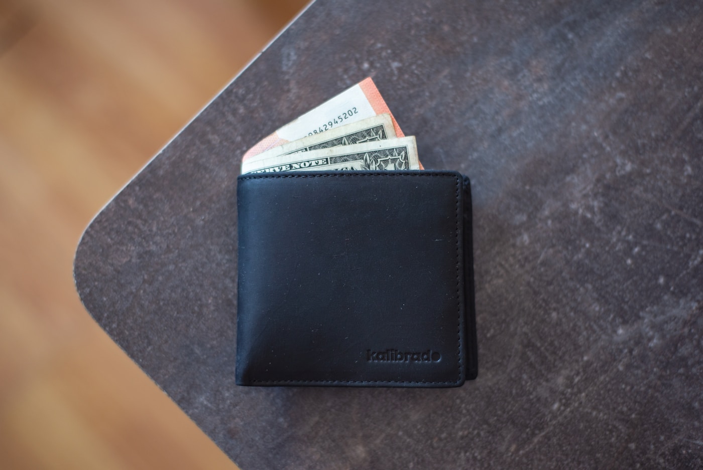 Black leather wallet with cash bills tucked inside