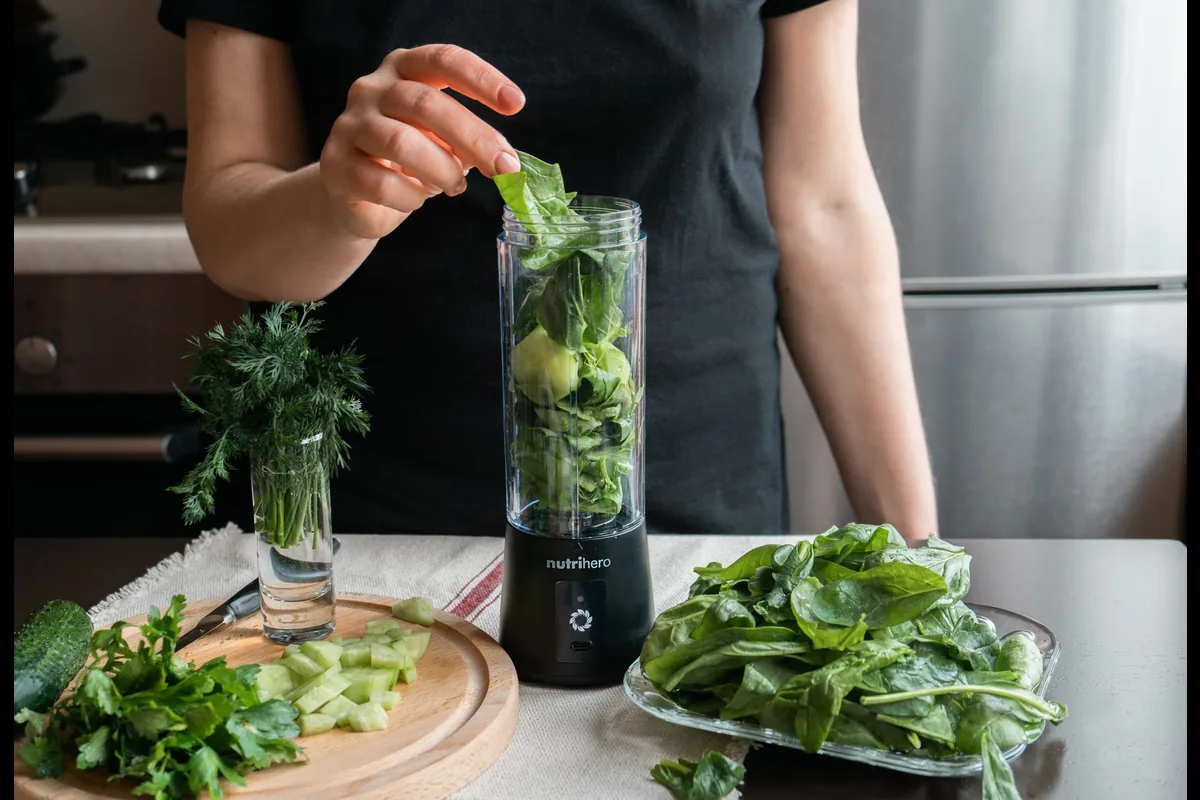 Preparing a fresh green smoothie with spinach and cucumber in a home kitchen