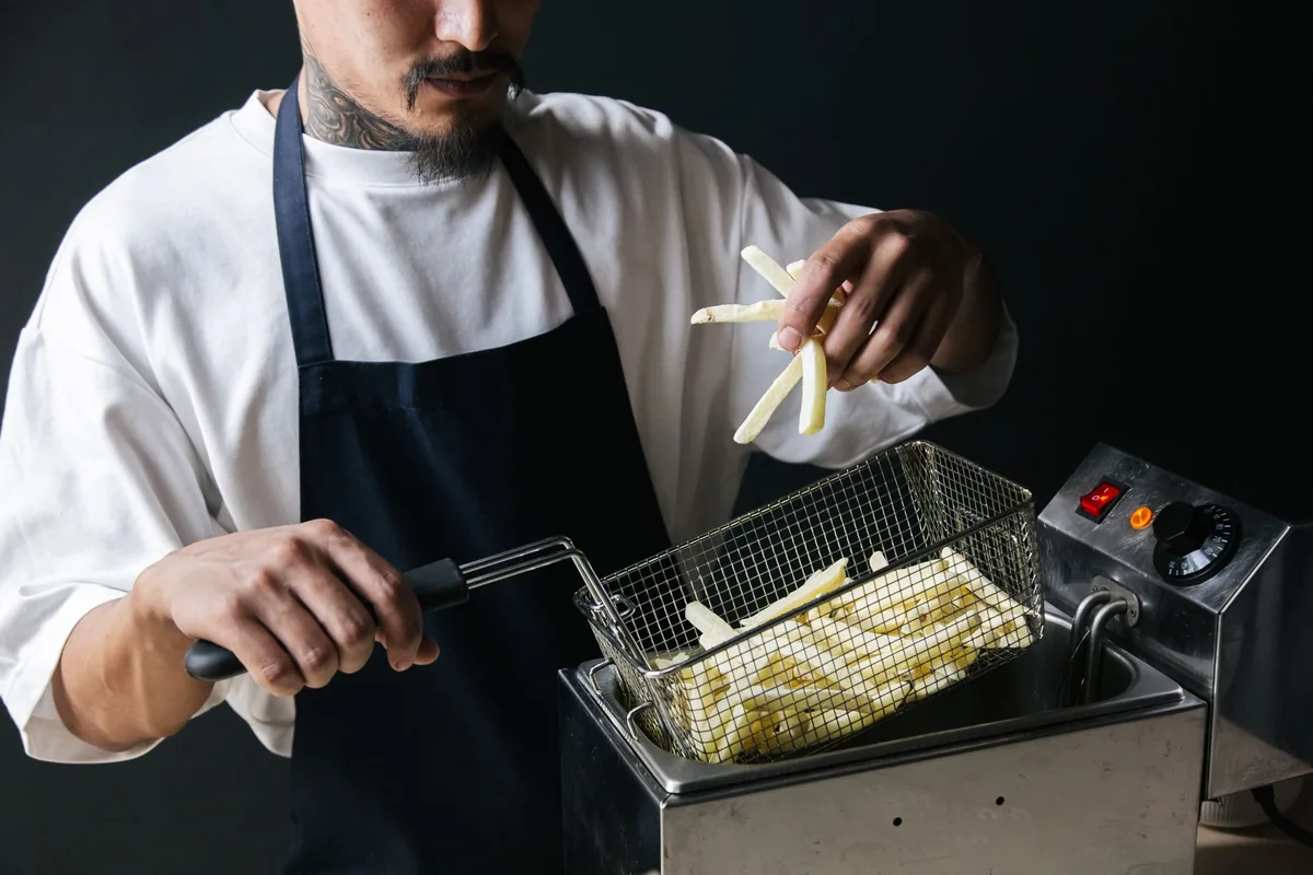 A chef lowering fries into a fryer basket