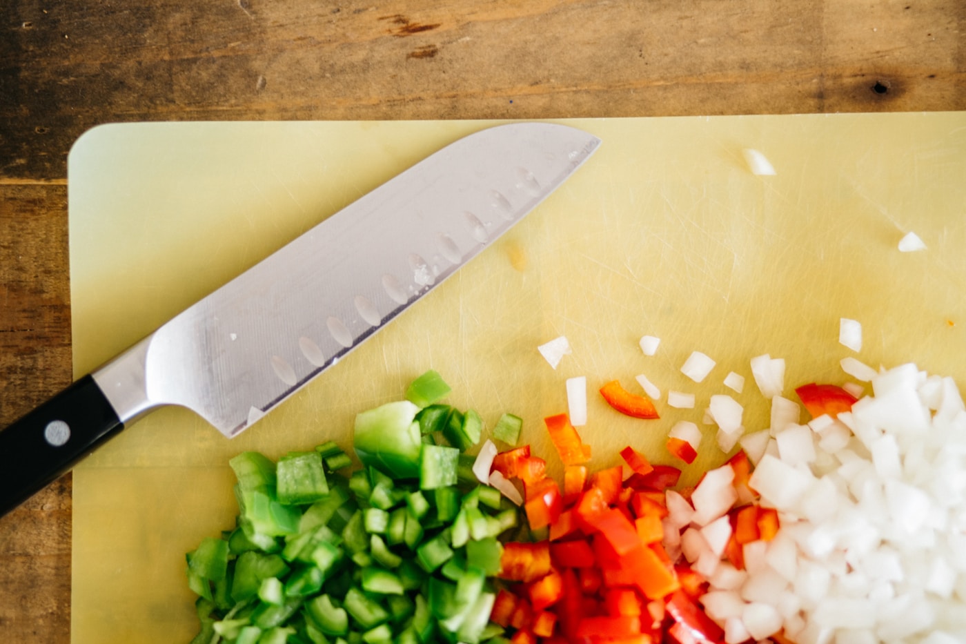 Diced green and red bell peppers with onion on a cutting board