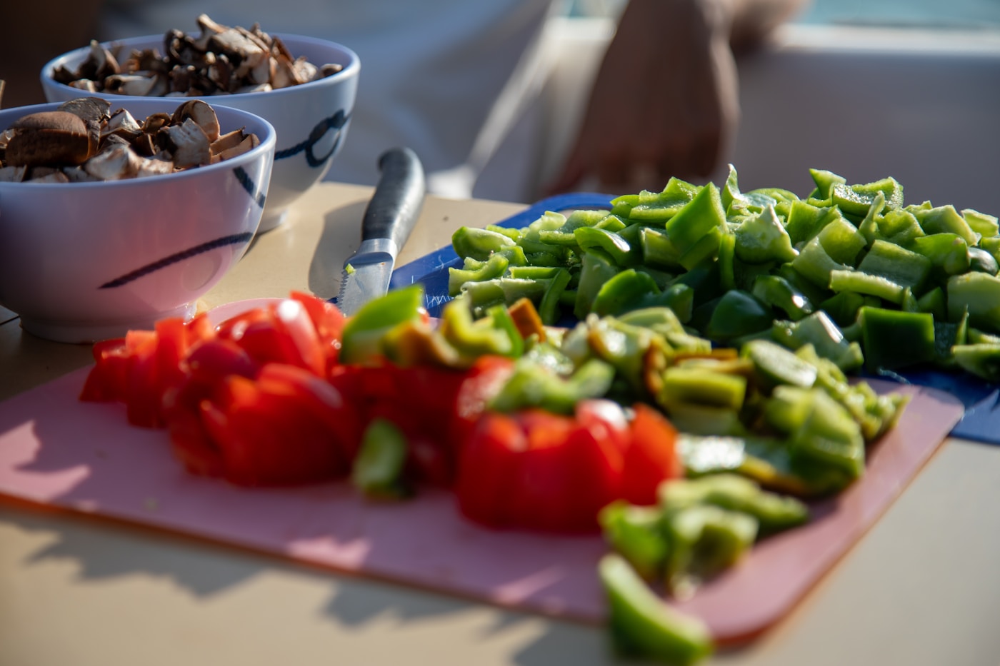 Fresh chopped bell peppers, tomatoes, and mushrooms on a cutting board