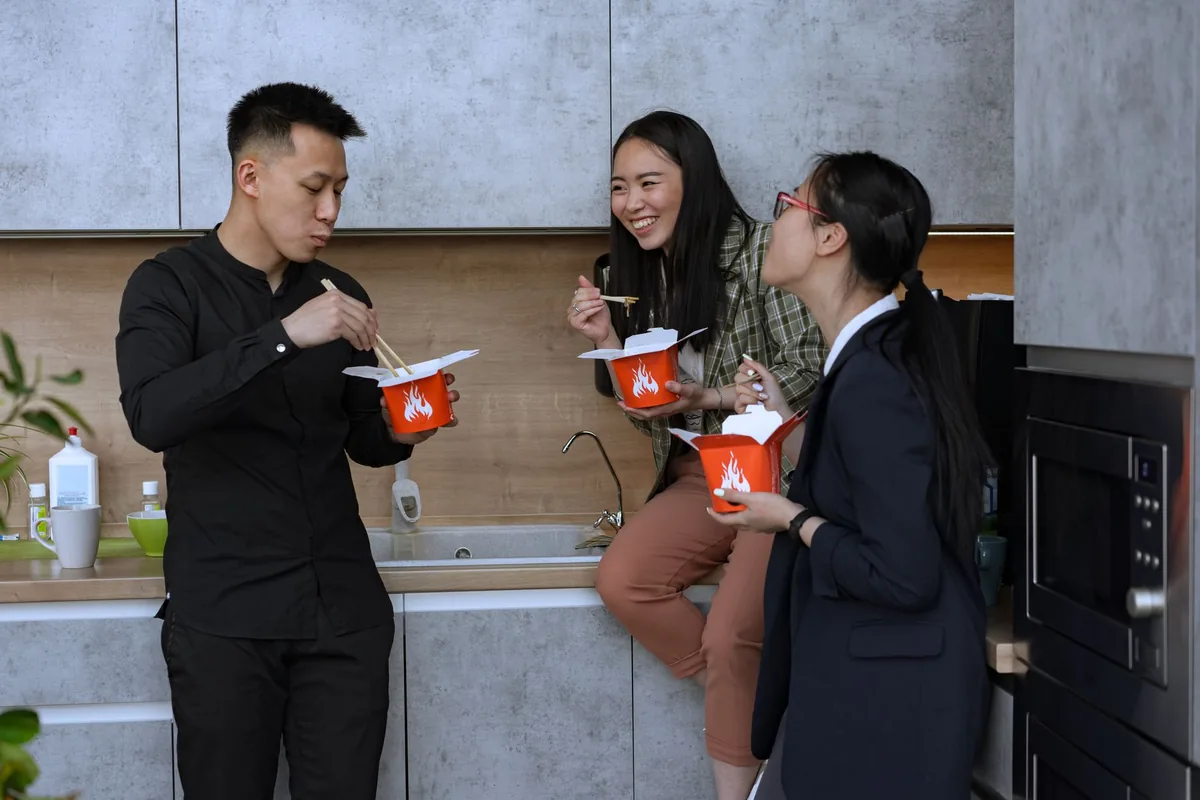 Colleagues reheating lunch in an office kitchen