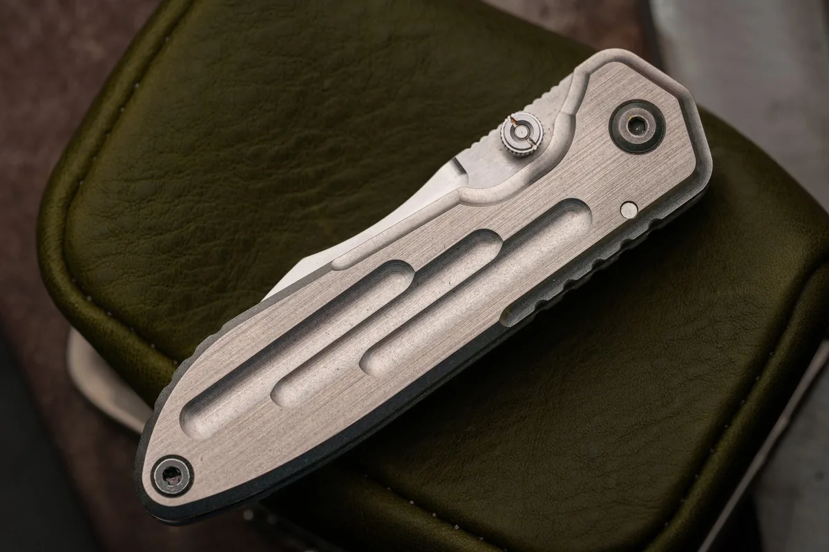 A compact folding knife on green leather