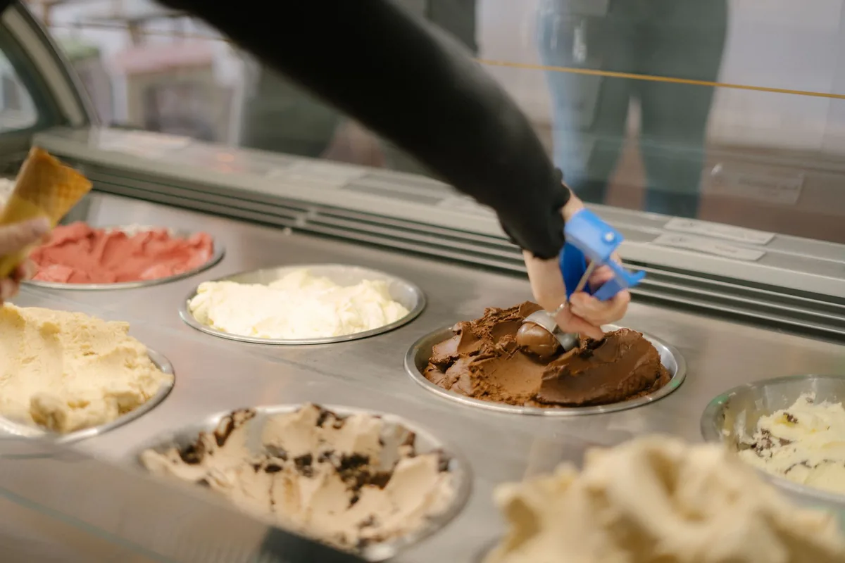 Hand scooping chocolate ice cream in a gelato shop