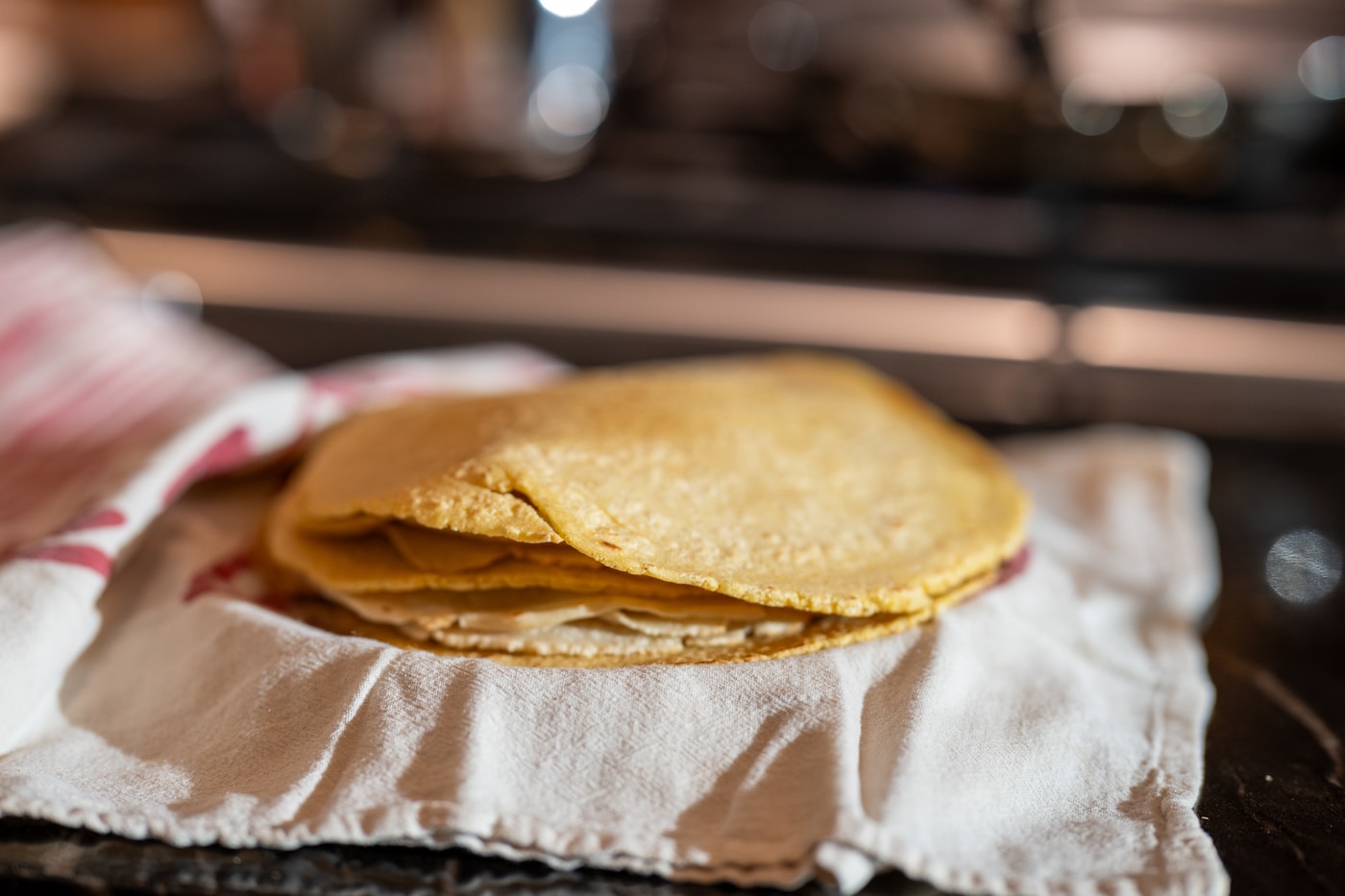 Stack of fresh corn tortillas folded on a cloth napkin