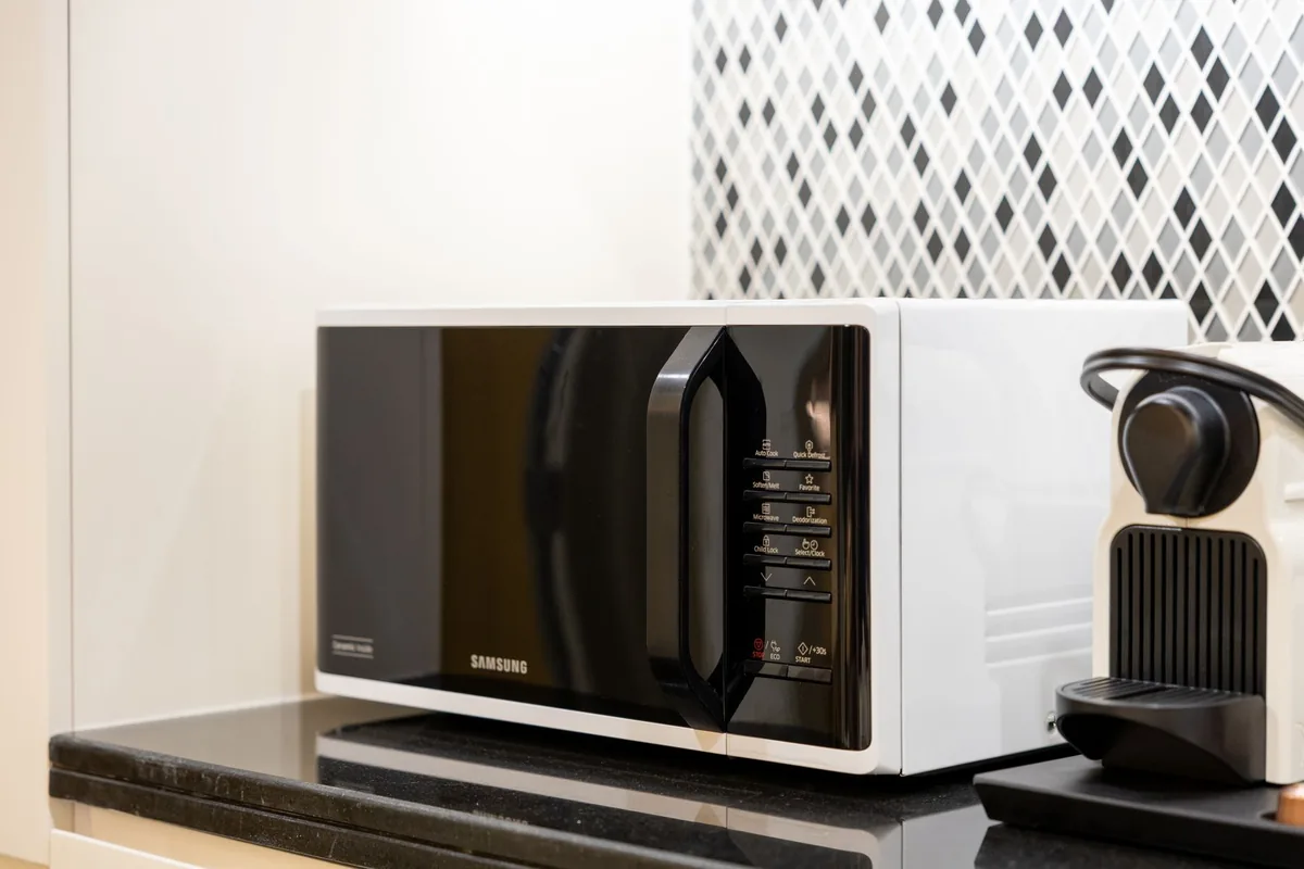 A black countertop microwave and coffee maker on a kitchen counter