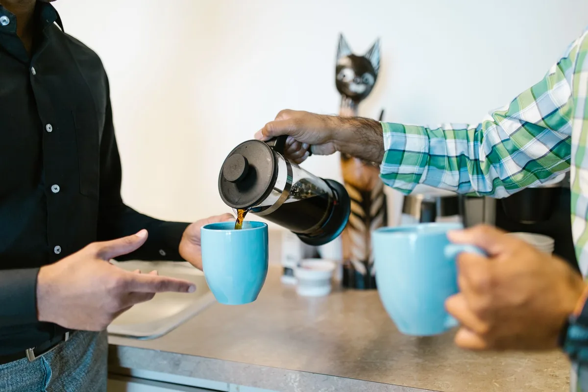 Coworkers pouring coffee into mugs in an office