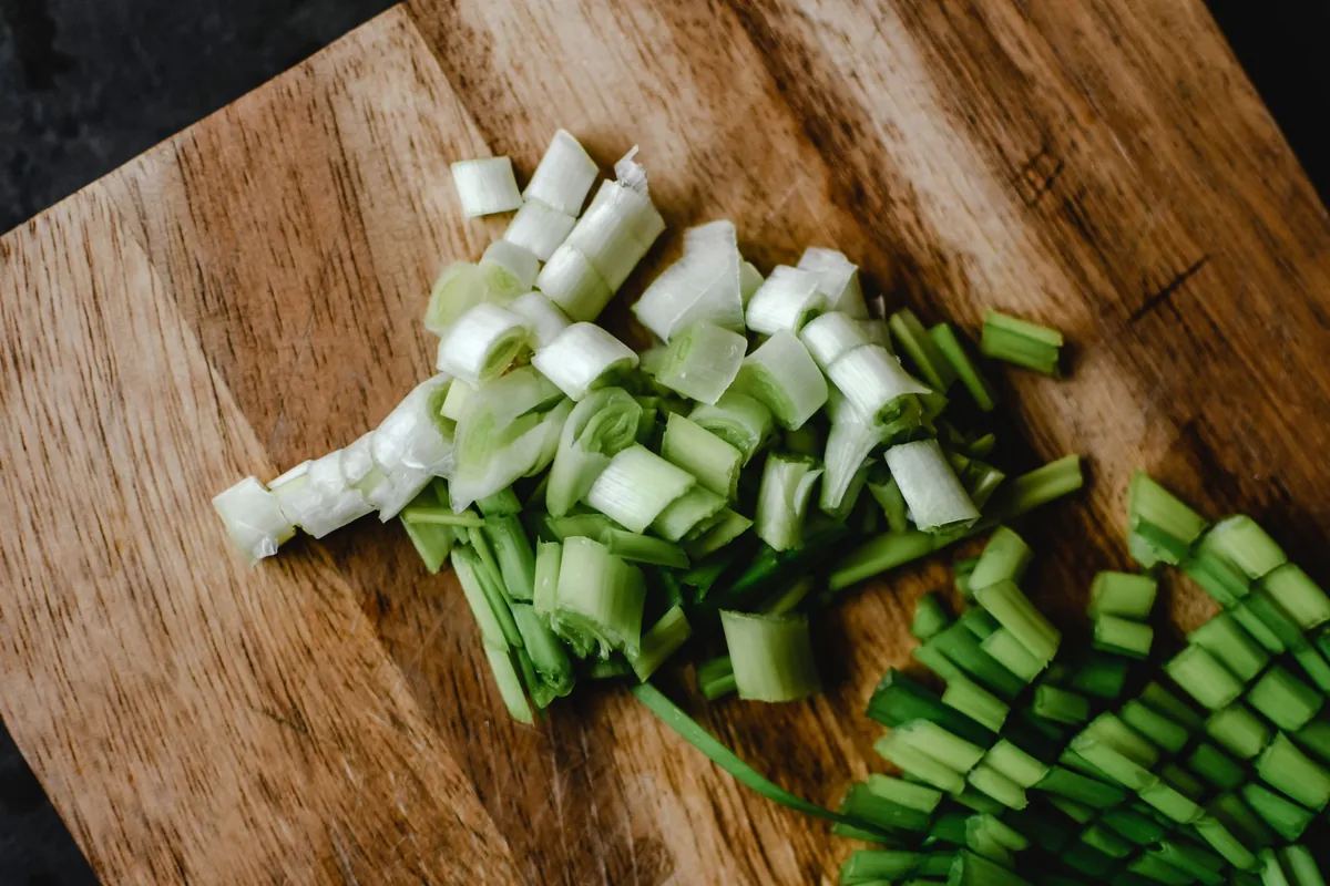 Chopped green onions on a wooden board