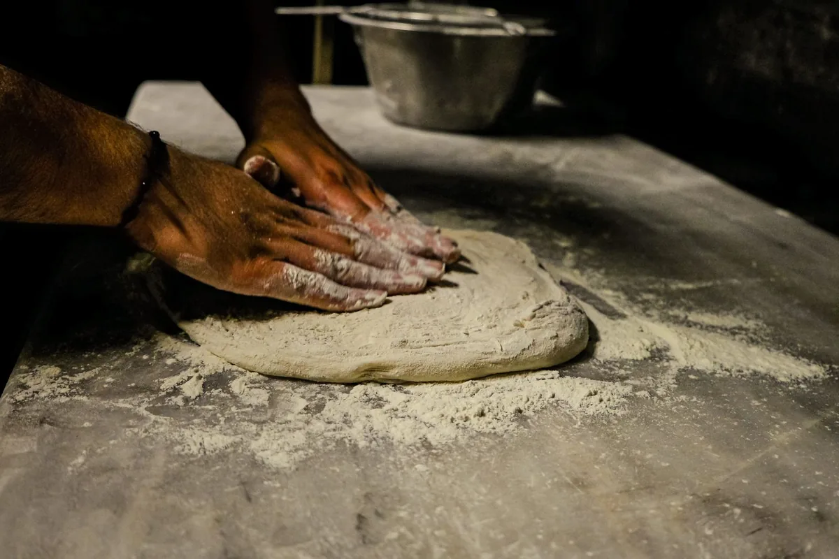 Hands kneading dough on a floured table