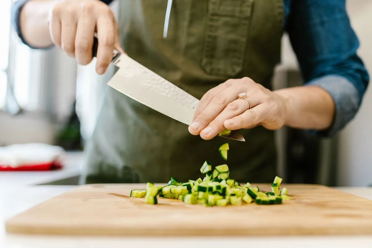 Chef slicing cucumbers on a wooden board