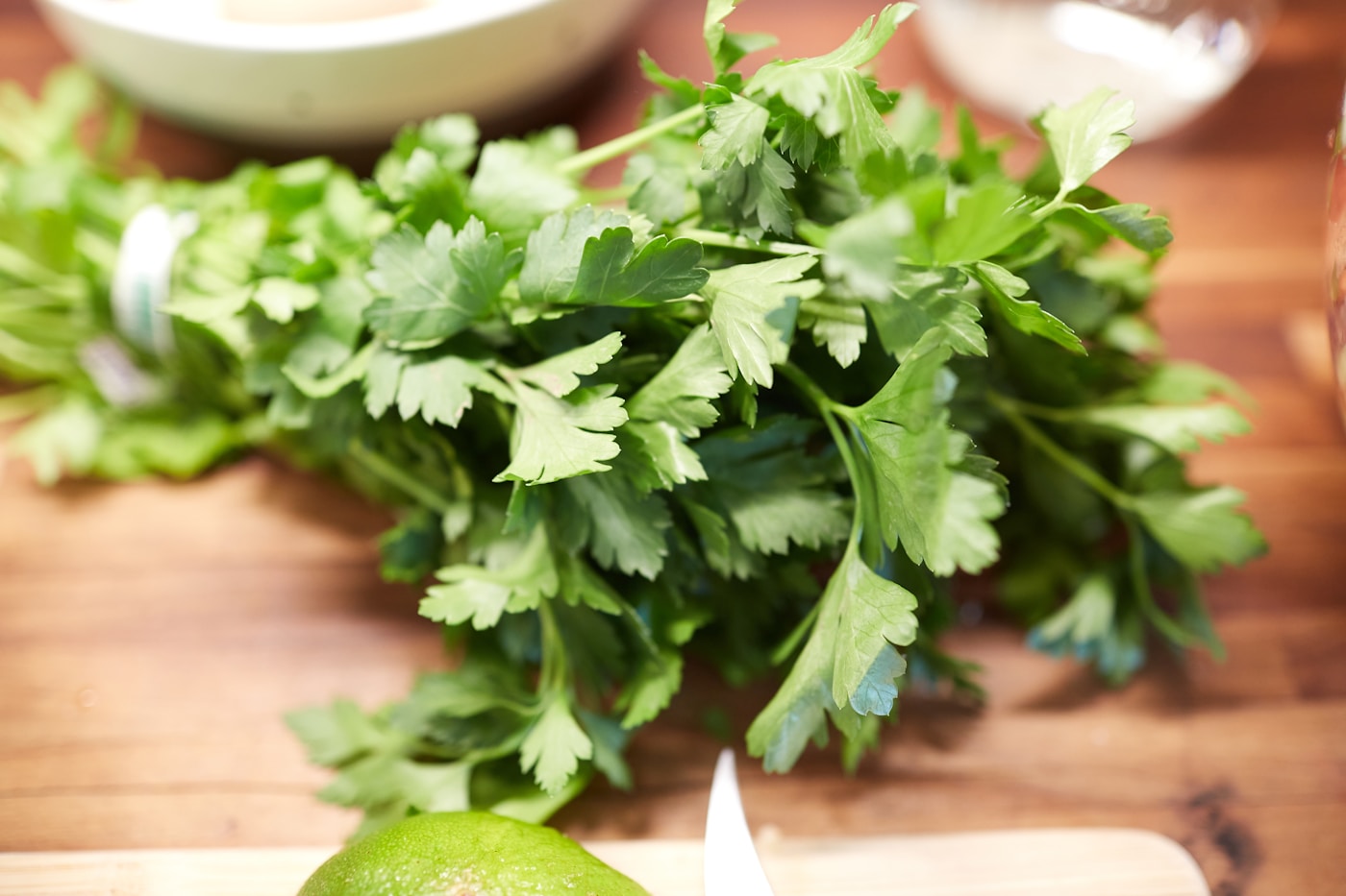 Fresh cilantro bunch on a wooden cutting board with lime