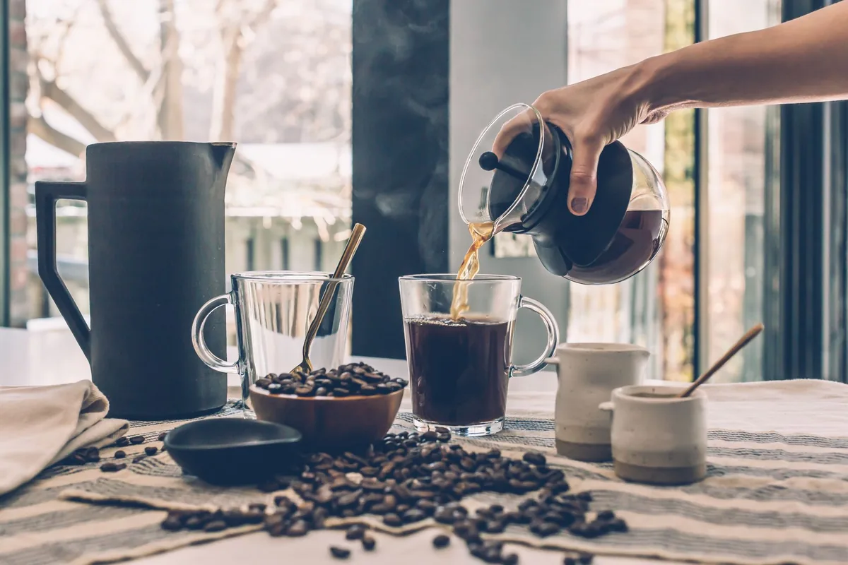Fresh coffee being poured with scattered beans