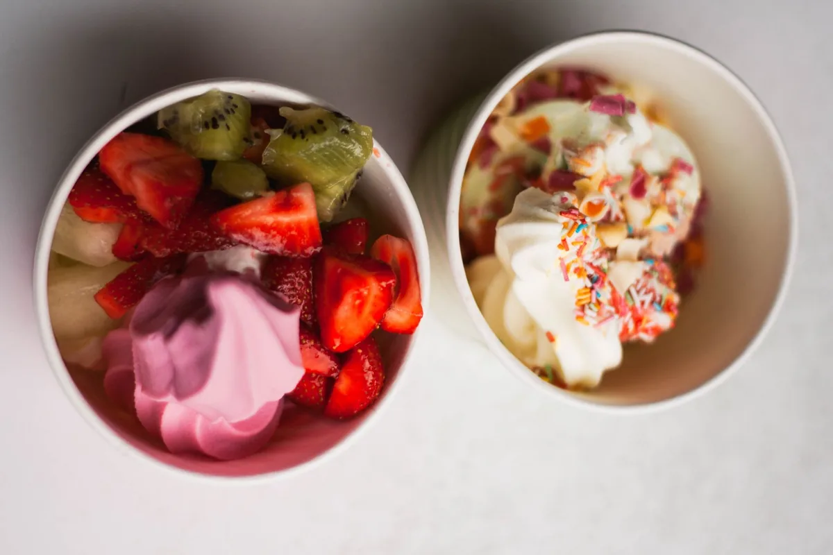 Two cups of frozen yogurt topped with fresh fruit