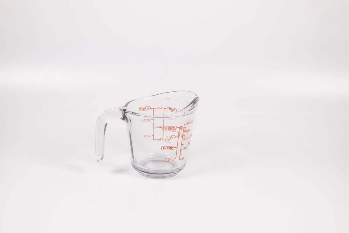A glass measuring cup with red markings
