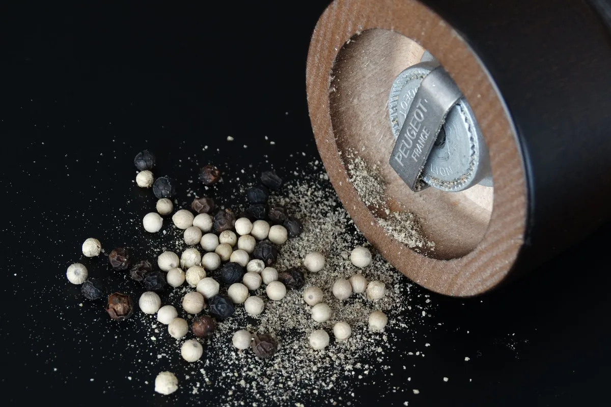 Grinding pepper over a dish