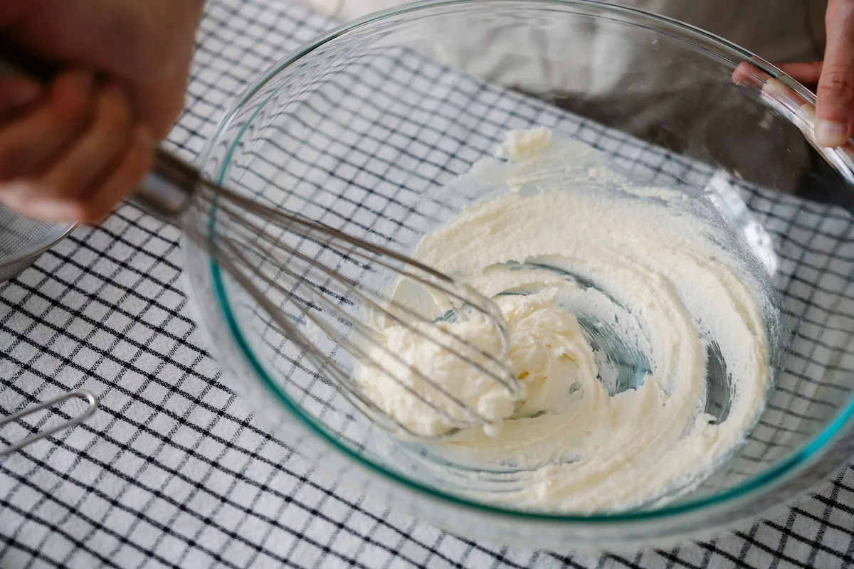 Whisking cream in a glass bowl, the job a hand blender whisk attachment is designed for