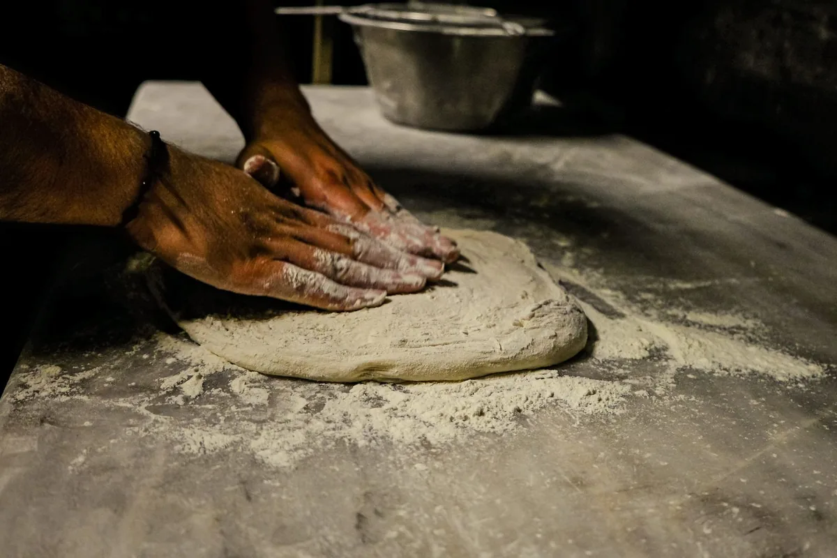 Hands kneading bread dough on a floured table