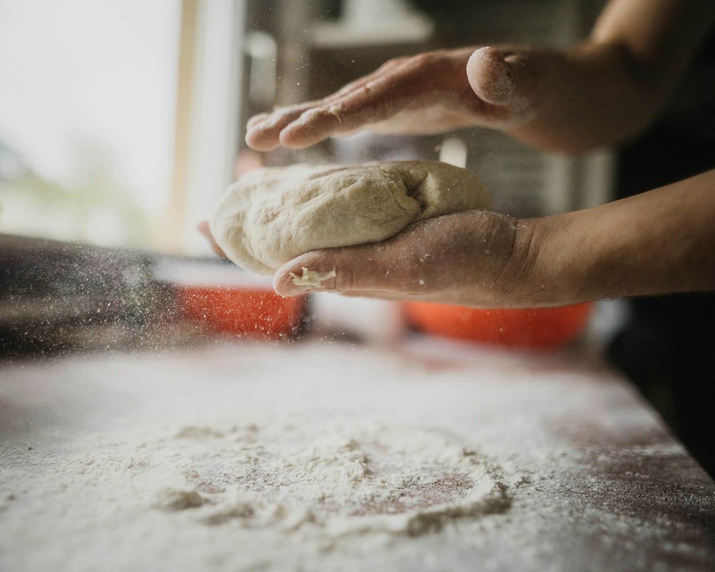 Hands kneading fresh pizza dough dusted with flour