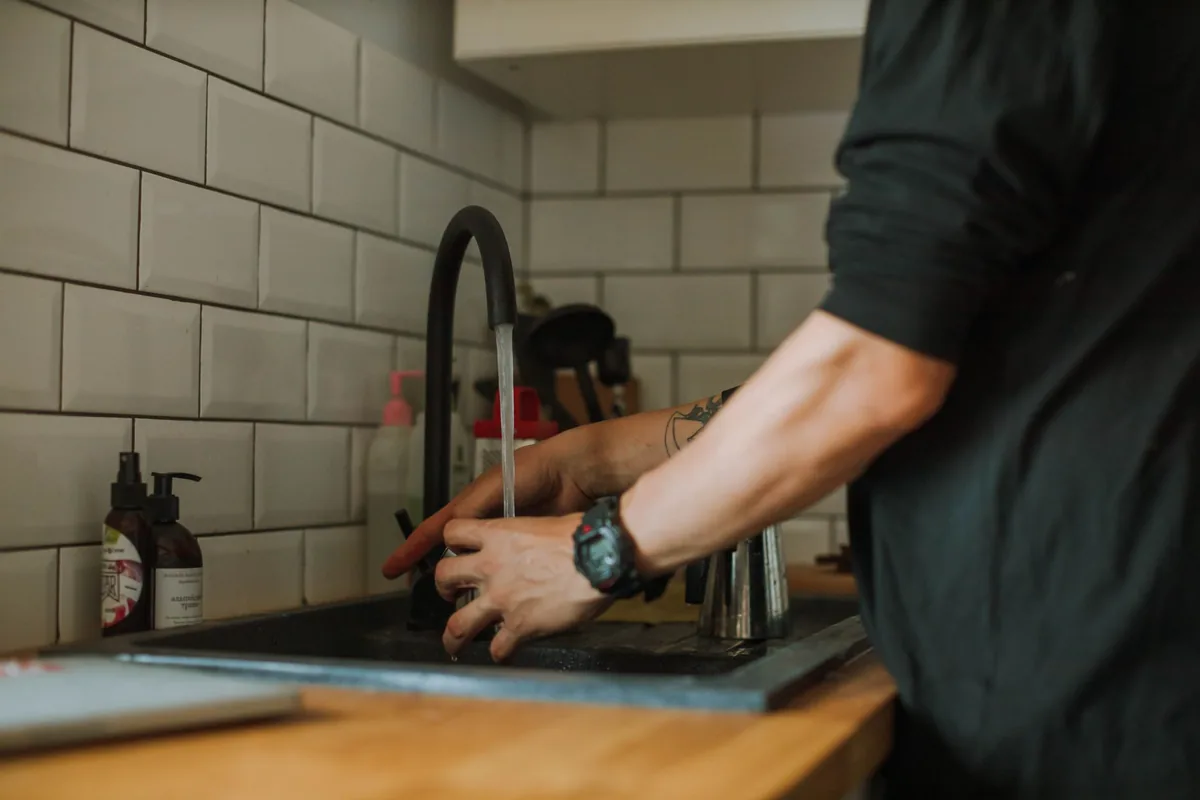 Hands lifting a mesh filter from a cooker hood