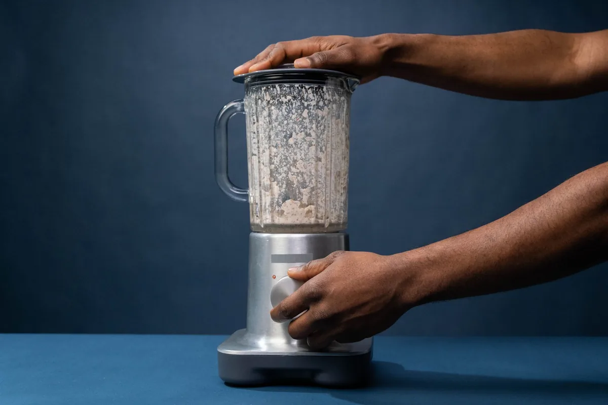 Hands operating a blender on a kitchen counter