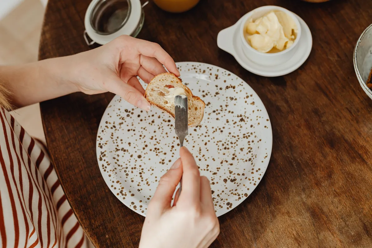 Person spreading butter on bread
