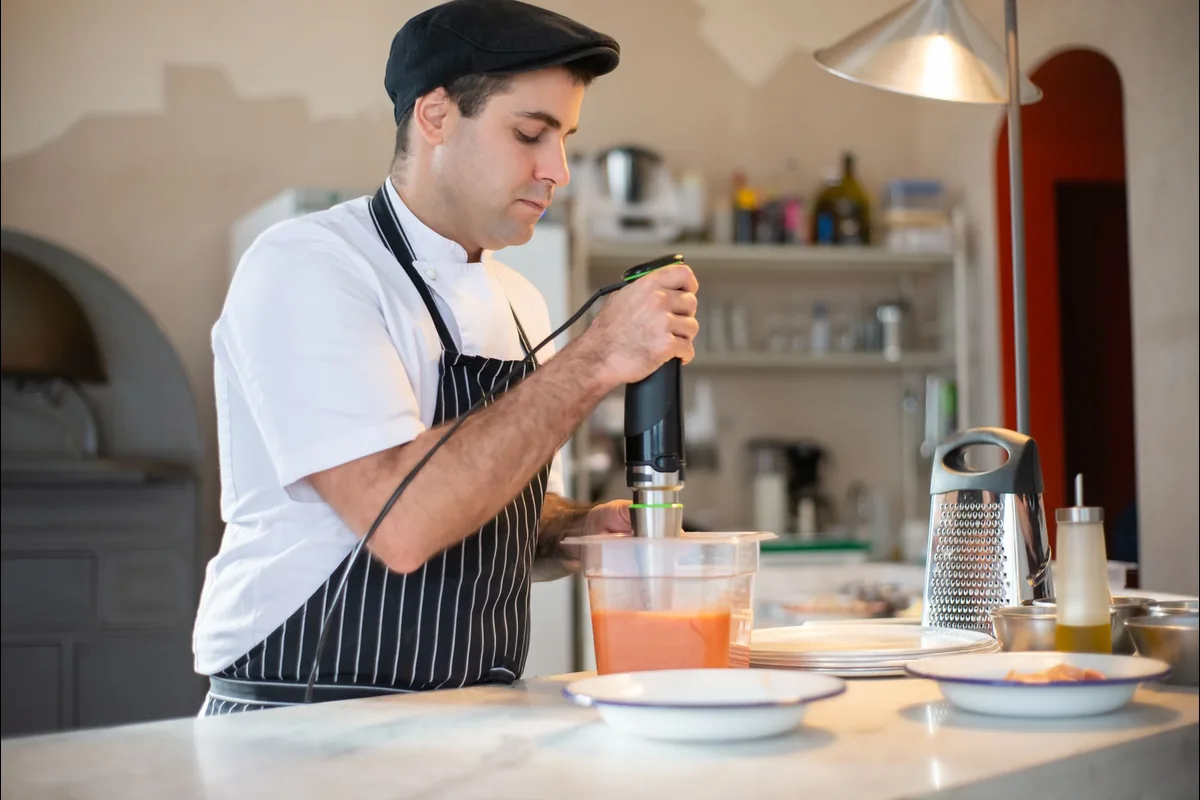 Cook blending ingredients in a modern kitchen, illustrating the criteria used to compare hand blenders
