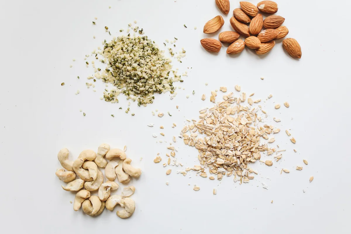 Almonds, cashews, oats and hemp seeds on a white surface