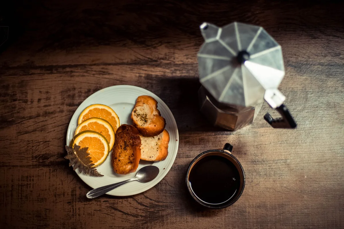 Warm breakfast scene with coffee, toast and orange slices