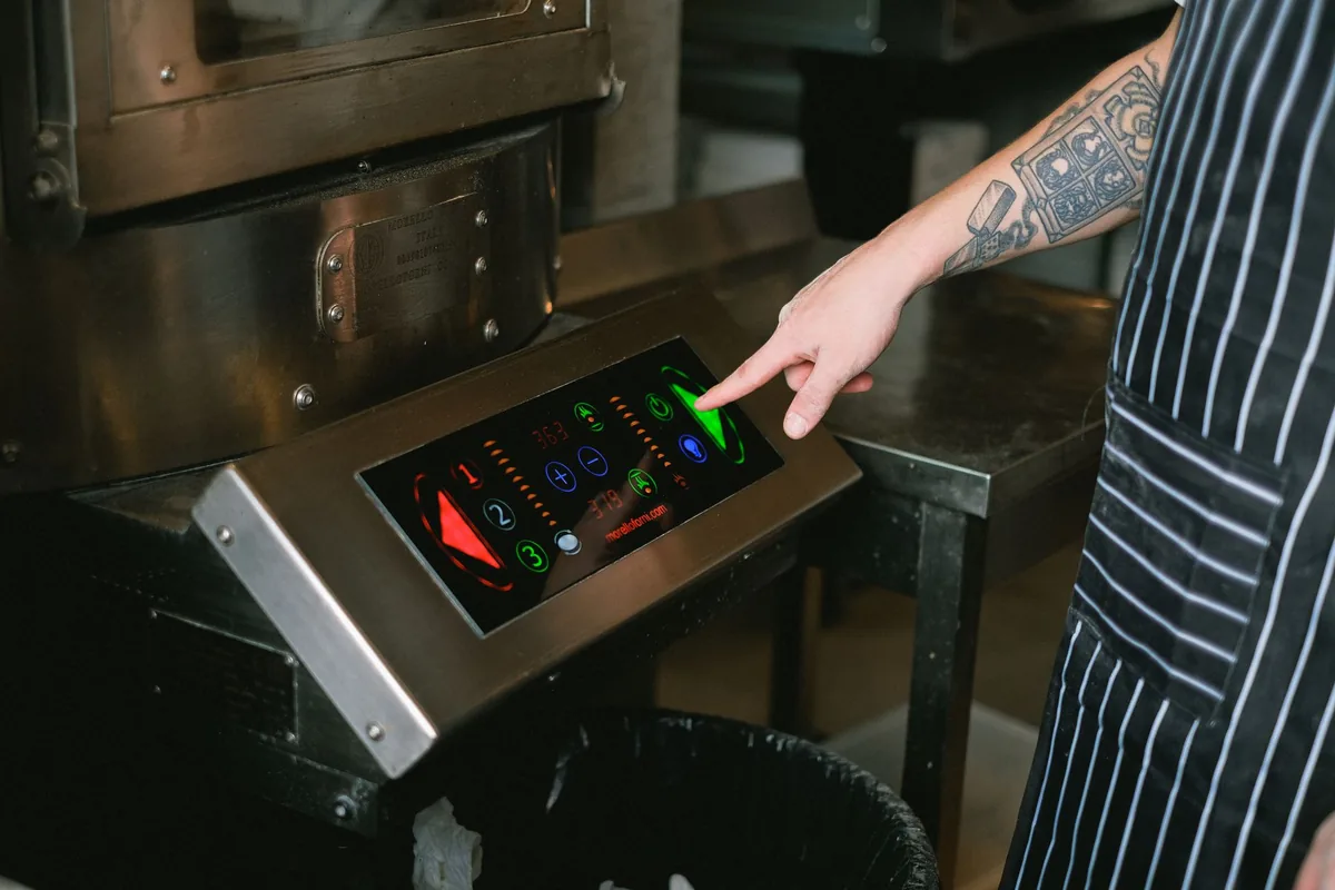 Chef using a touchscreen control panel in a modern kitchen