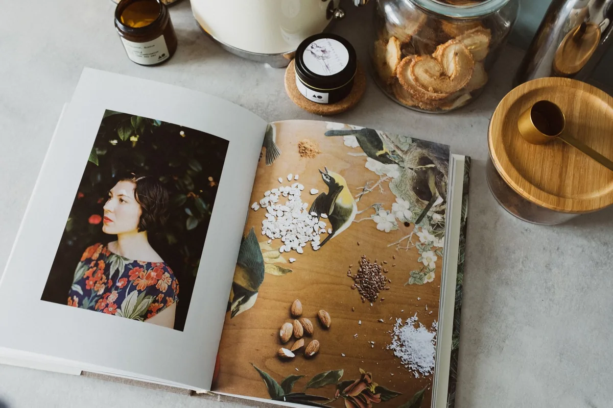 Opened recipe book in a kitchen among jars of ingredients