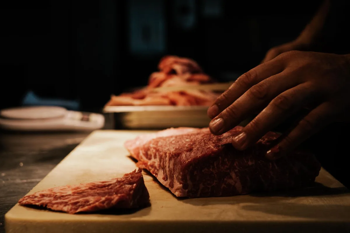 Chef preparing marbled beef on a wooden board