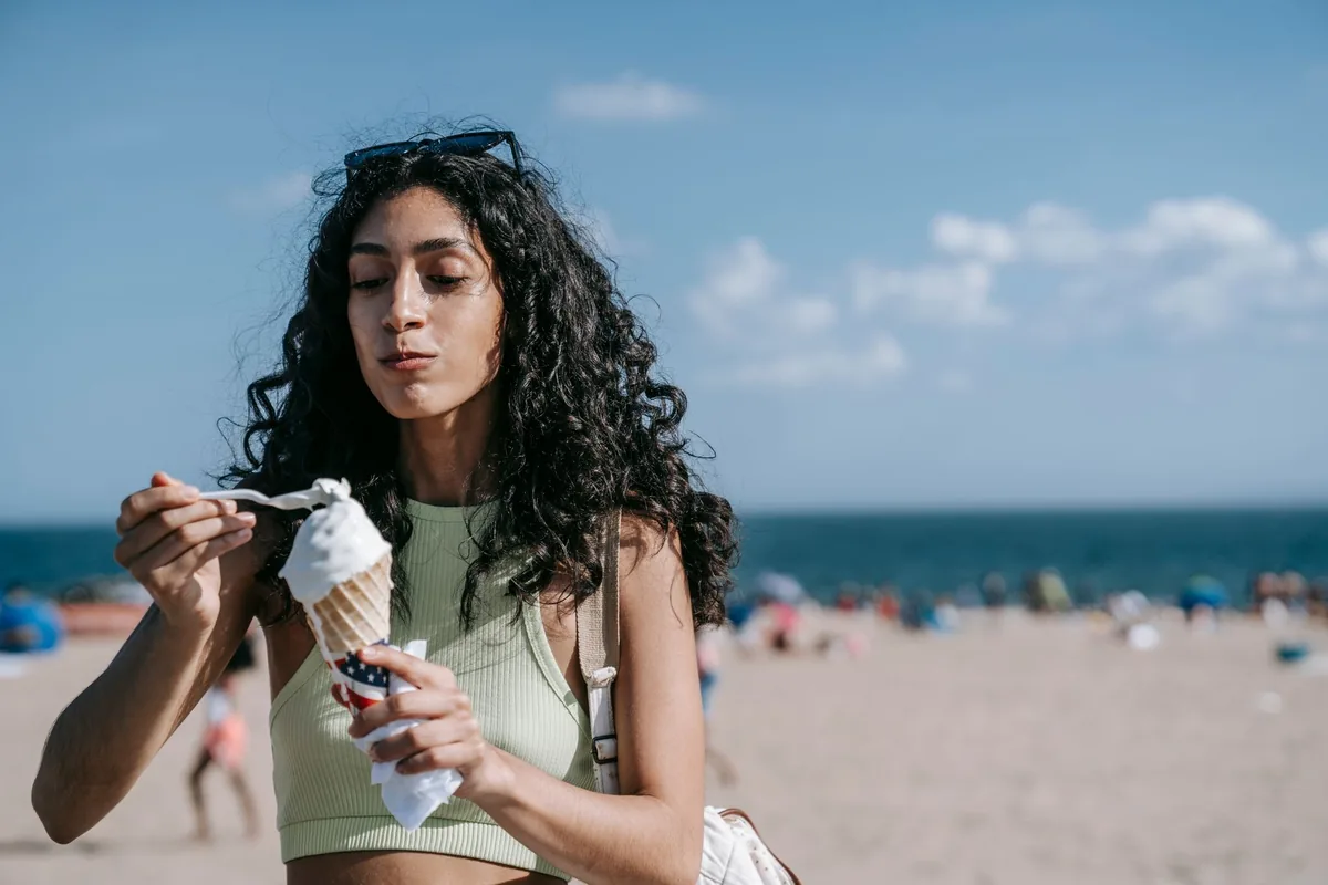 Woman enjoying an ice cream cone on a sunny beach