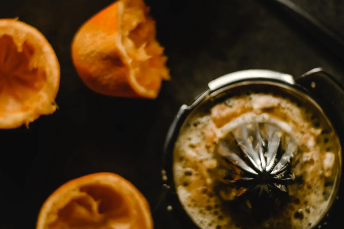 Juiced oranges beside a citrus juicer