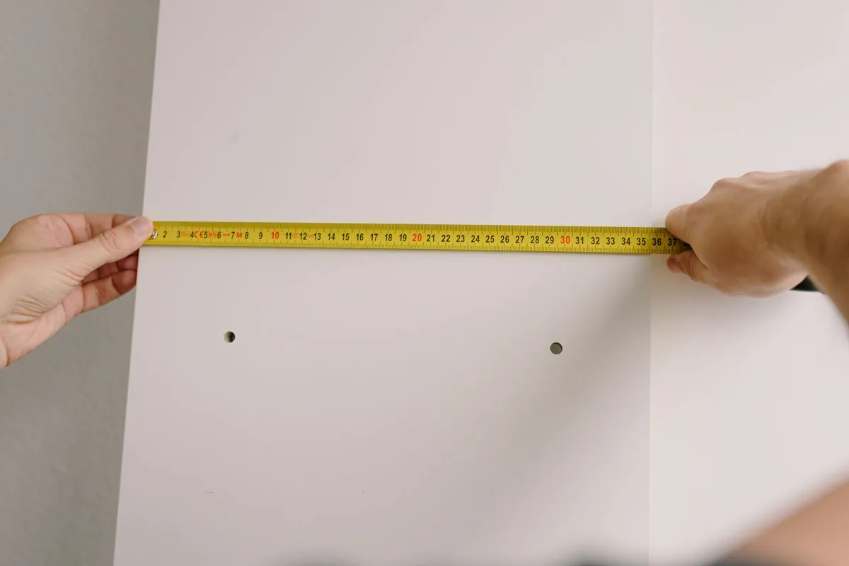 Person marking drill holes on a kitchen wall