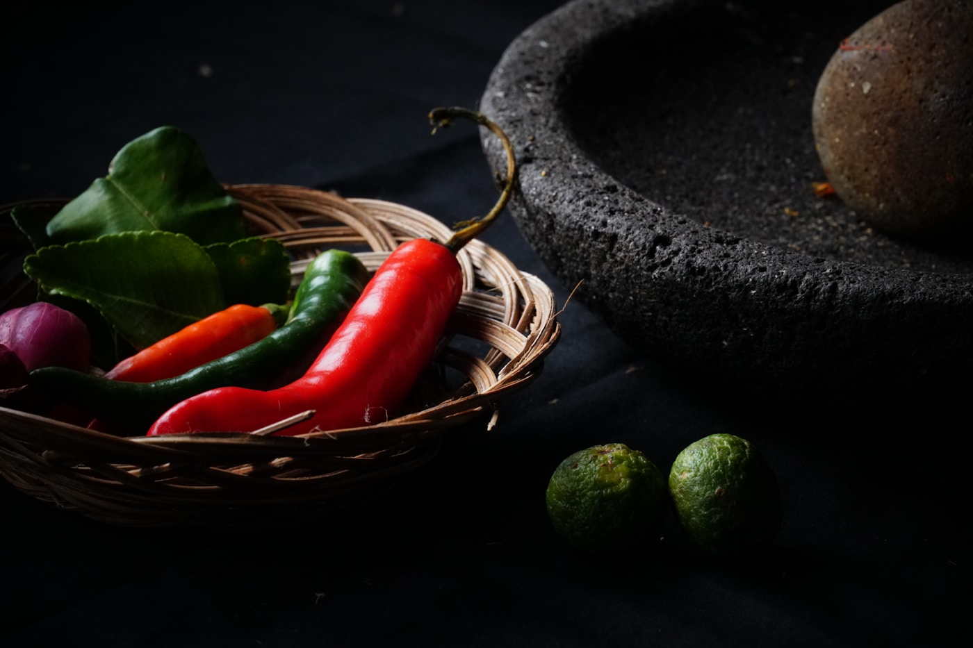 Fresh chili peppers, limes, and a stone mortar used for Mexican meat marinades