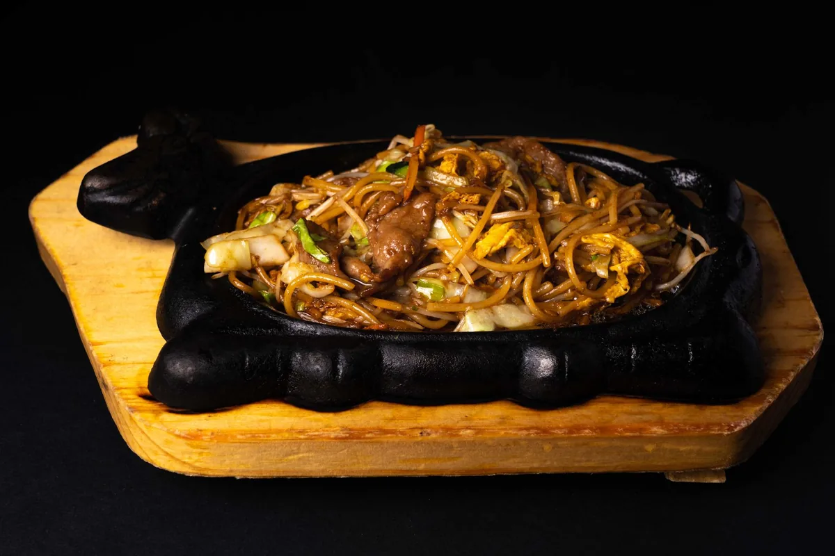 Stir-fry noodles served on a sizzling cast iron plate