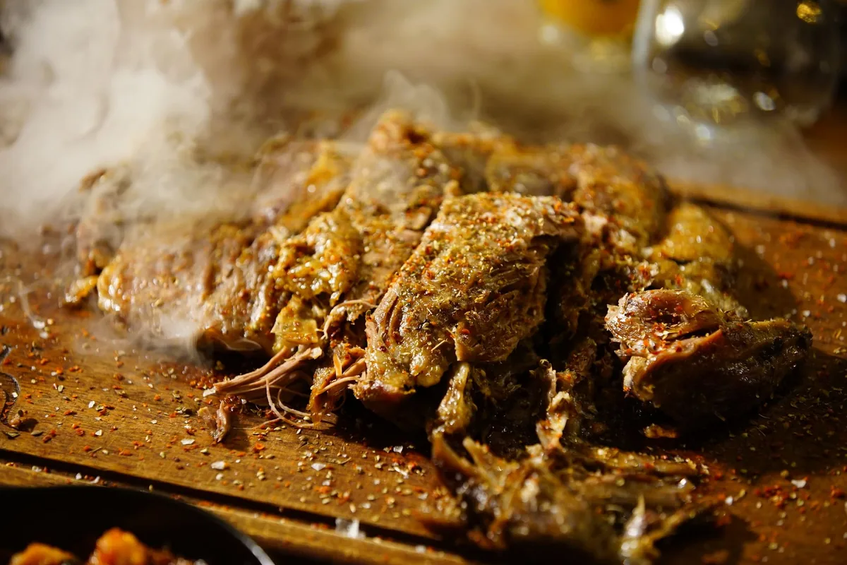 Steaming pulled pork seasoned with spices on a wooden board