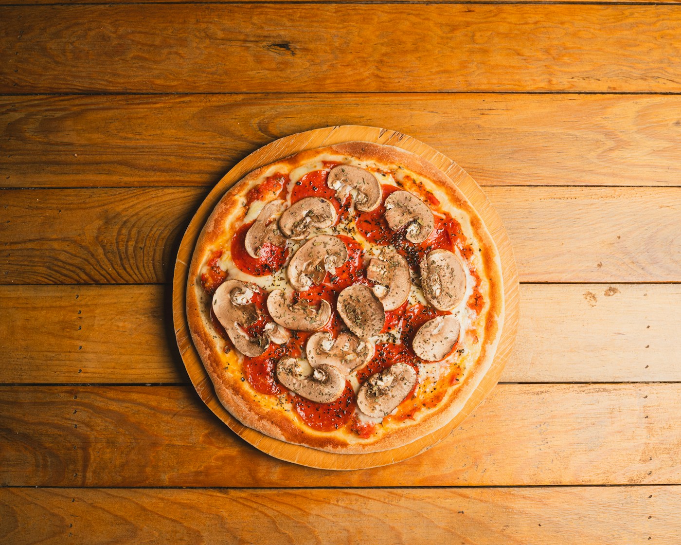 Overhead view of a pizza topped with sliced mushrooms and tomato sauce