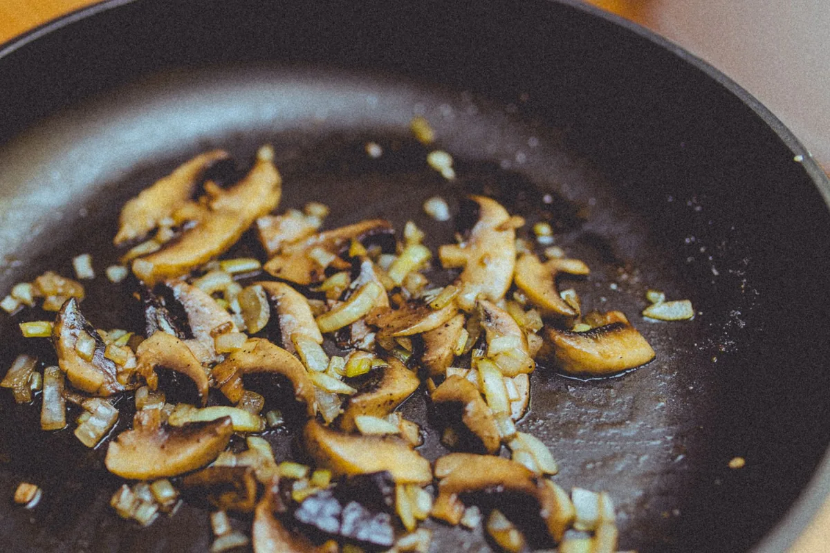 Mushrooms and onions sauteing in a skillet