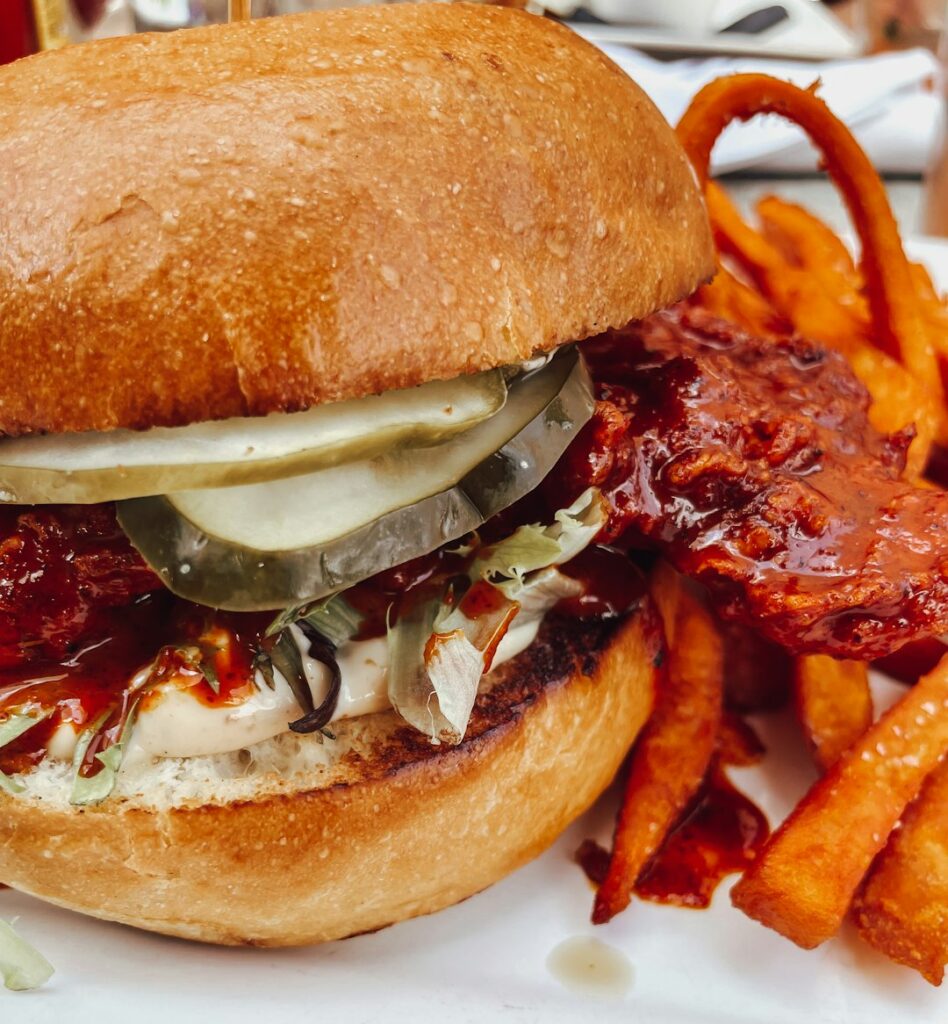 BBQ chicken cheesesteak sandwich with pickles, served with sweet potato fries