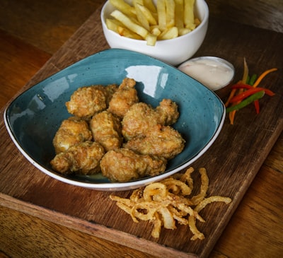 Breaded boneless wings in a blue bowl with fries
